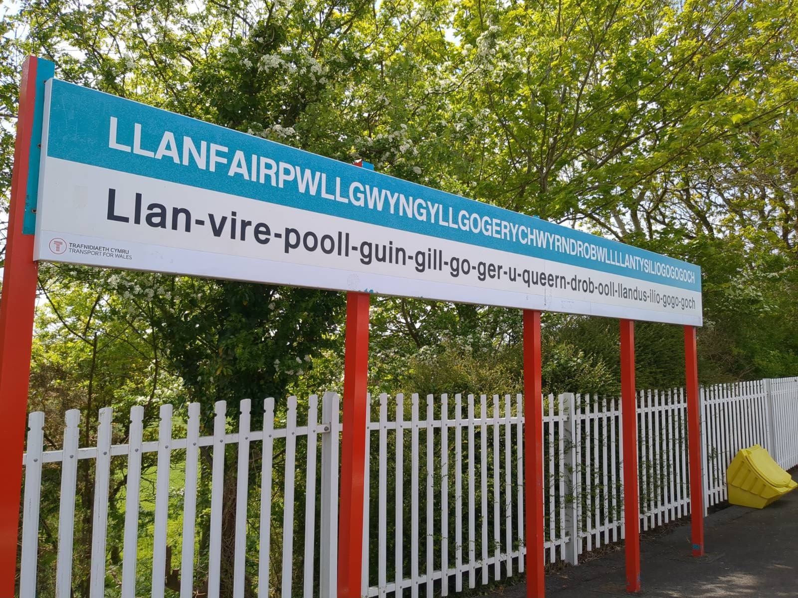 A photo of the famous sign of Llanfairpwll station with the full name of the village on it